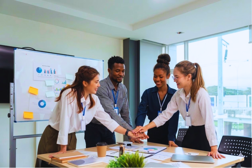 Diverse business team joining hands together in office meeting room showing teamwork and collaboration